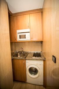 a kitchen with a washing machine and a microwave at Hostal Caballeros in Soria