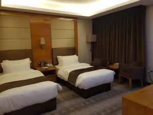 um quarto de hotel com duas camas e uma mesa e cadeiras em Gloria Hotel em Amã