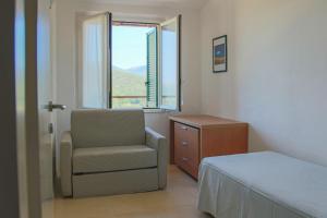 a bedroom with a bed and a chair and a window at Allegroitalia Elba Golf in Portoferraio