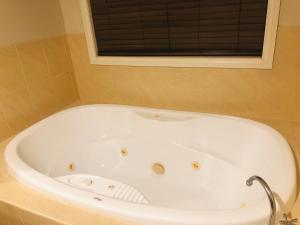 uma banheira branca na casa de banho com uma janela em Golf View Charm em Craigieburn