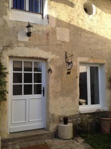 a stone building with a white door and twowindows at Ferme de Pontaly in Bailly