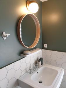 y baño con lavabo blanco y espejo. en Domaine les Bruyères en Gambais