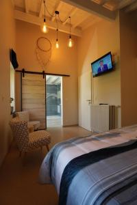 1 dormitorio con 1 cama y TV en la pared en Le Sorbier - Gîte et chambres d'hôtes en Malmedy