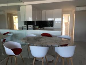 cocina con mesa y sillas blancas en Appartement de standing face à la mer avec vue exceptionnelle sur les îles de Lerins en Mandelieu-la-Napoule