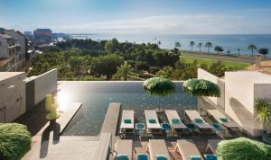 a pool with chairs and umbrellas and the ocean at El Llorenc Parc de la Mar - Adults Only (+16) in Palma de Mallorca