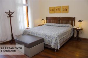 a bedroom with a bed, desk, lamp, and dresser at Hotel Villa Michelon in Bento Gonçalves