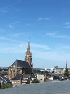 une église avec une tour d'horloge dans une ville dans l'établissement Duplex residence d'orléans, à Amiens