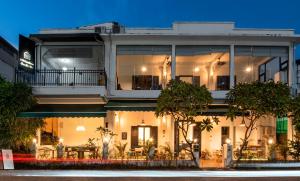 a large white building with trees in front of it at SYRI Guesthouse Vientiane Hostel & Cafe in Vientiane