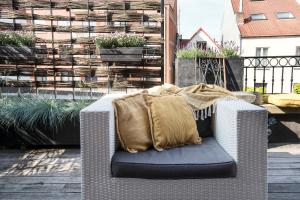 a wicker chair with a blanket on a patio at Ganda Rooms & Suites in Ghent