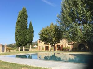 a swimming pool in front of a house with trees at VILLA Podere IL GIARDINO in Castiglion Fiorentino