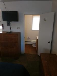 a bedroom with a bathroom with a toilet and a television at The Ohio Motel in Bath