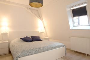 a white bedroom with a bed with two blue pillows at Petite Venise Grand Duplex Turenne Hyper Centre in Colmar