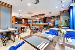 un restaurante con mesas de madera y sillas azules en HOTEL NUMBER ONE BY GRANO Gdańsk, en Gdansk