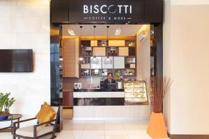 un hombre sentado en el mostrador de una cafetería en Mida Hotel Ngamwongwan - SHA Plus, en Nonthaburi