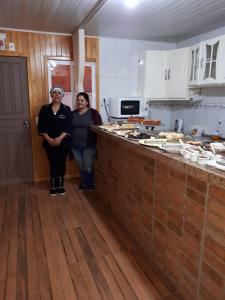 two women standing in a kitchen with a counter at Pousada Amelia in Urubici
