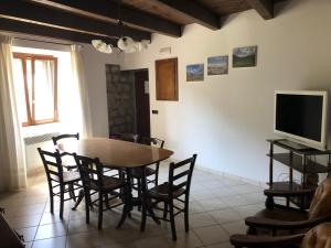 ein Esszimmer mit einem Tisch, Stühlen und einem TV in der Unterkunft Casa Vacanze Bello in Pietraroia