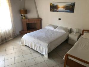 ein Schlafzimmer mit einem weißen Bett und einem Kamin in der Unterkunft Casa Vacanze Bello in Pietraroia