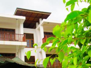 a white building with a balcony and a tree at Shanika Beach Inn in Tangalle