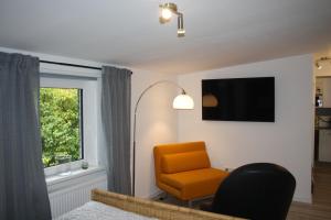 a living room with an orange chair and a window at 5 FeWo's Harztraum in Innenstadt mit kostenlosem Parkplatz von Harztraveler in Wernigerode
