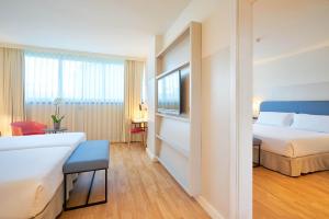 a hotel room with a bedroom with a bed and a tv at Eurostars Málaga in Málaga