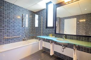 a bathroom with a sink and a tub and a mirror at Eurostars Málaga in Málaga