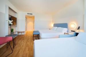 a hotel room with two beds and a table and chairs at Eurostars Málaga in Málaga