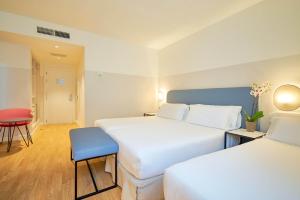 a hotel room with two beds and a chair at Eurostars Málaga in Málaga