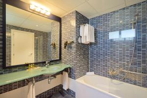 a bathroom with a sink and a tub and a mirror at Eurostars Málaga in Málaga
