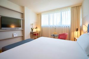 a hotel room with a large bed and a television at Eurostars Málaga in Málaga