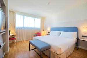 a bedroom with a large white bed with a blue headboard at Eurostars Málaga in Málaga