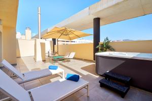 a patio with chairs and an umbrella on a roof at Eurostars Málaga in Málaga