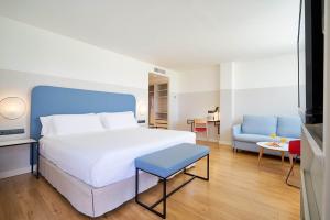 a bedroom with a large white bed and a blue chair at Eurostars Málaga in Málaga