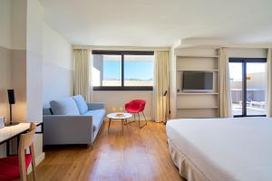 a hotel room with a bed and a couch and a chair at Eurostars Málaga in Málaga