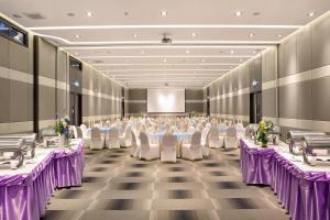 a banquet hall with tables and chairs and a screen at Mida Hotel Ngamwongwan - SHA Plus in Nonthaburi