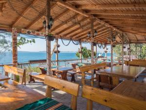 a restaurant with wooden tables and benches and the ocean at Hotel Fantasy Beach in Sveti Vlas