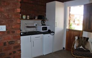 a kitchen with white cabinets and a brick wall at Aranos Kalahariland Guest Farm in Aranos