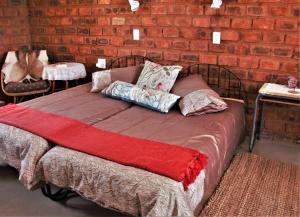 a bed with pillows on it in front of a brick wall at Aranos Kalahariland Guest Farm in Aranos