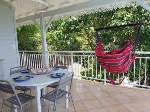 a porch with a table and chairs and a hammock at GITE REVE CARAIBES LE PETIT HAVRE in Bouillante