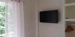 TV de pantalla plana en una pared junto a una ventana en GITE REVE CARAIBES LE PETIT HAVRE, en Bouillante