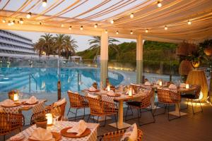 een restaurant met tafels en stoelen en een zwembad bij Santa Monica Suites Hotel in Playa del Inglés