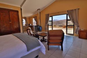 a bedroom with a bed and a desk and a chair at De Ark Mountain Lodge in Clarens