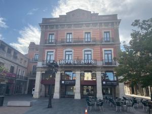 a hotel with tables and chairs in front of a building at Hotel Suís in Sant Celoni