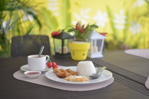 einen Tisch mit einem Teller Essen und einer Tasse Kaffee in der Unterkunft Casa Bicolandia Suites in Locsin