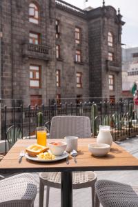 einen Holztisch mit Frühstücksspeisen und Getränken darauf in der Unterkunft Hotel Principal in Mexiko-Stadt