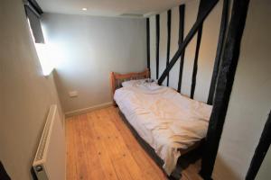 a bed in a room with a wooden floor at Best located and beautifully renovated cottage in Diss +2 photos