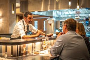 a chef preparing food in a restaurant kitchen at El Llorenc Parc de la Mar - Adults Only (+16) in Palma de Mallorca +37 photos