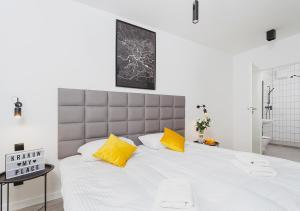 sypialnia z dużym białym łóżkiem z żółtymi poduszkami w obiekcie Aaron Aparthotel w Krakowie