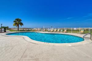 a swimming pool with blue water and a palm tree at Plantation Dunes II in Gulf Shores
