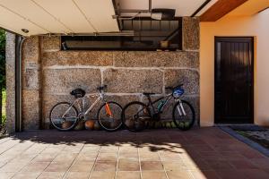 Dos bicicletas están estacionadas contra una pared de piedra. en Casa do Casal en Guimarães