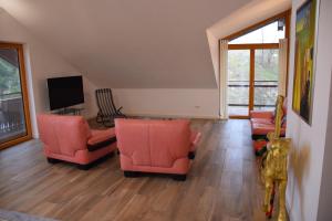 uma sala de estar com cadeiras laranja e uma televisão em Ferienwohnung Kaps em Aying